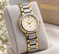 Sapphire Seiko Avenue 1F21-0H50 ladies’ quartz two-tone watch with gold accents, displayed on branded cushion.