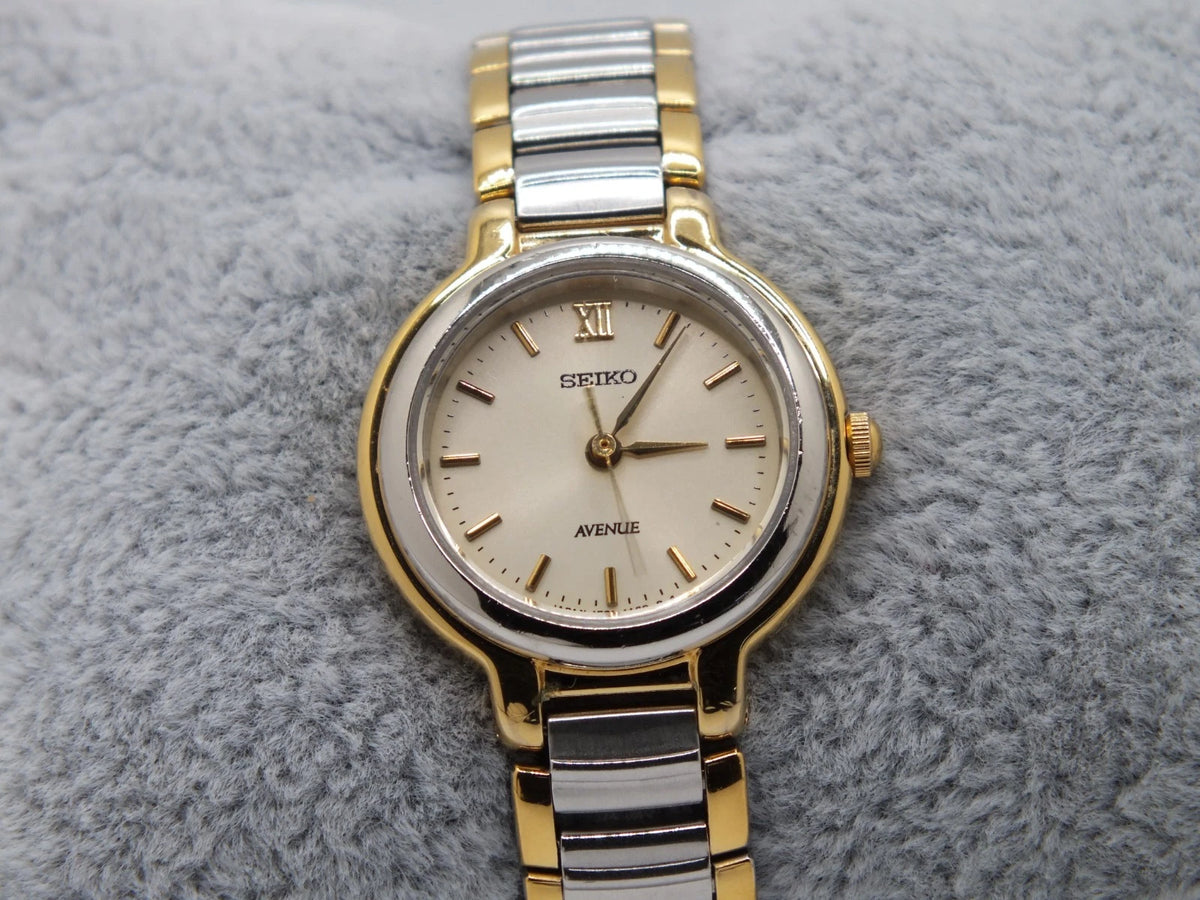 Sapphire Seiko Avenue 1F21-0H50 ladies’ quartz two-tone watch with gold accents, white dial, and gold hour markers.
