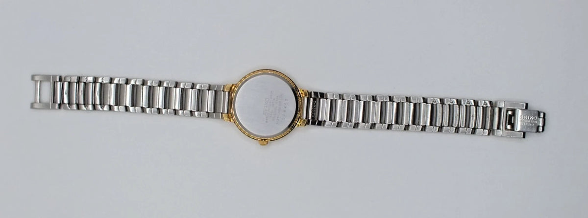 Seiko Avenue 1F21-0H50 ladies quartz two tone watch with gold band, silver bezel, and black dial on white background.