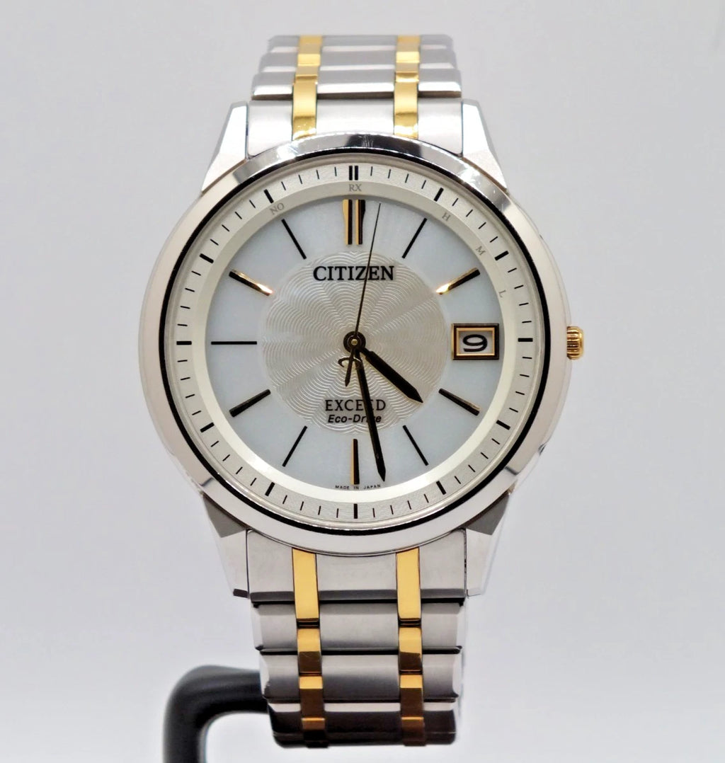 Citizen Exceed H113 Eco-Drive titanium two-tone watch with blue dial, gold hour markers, and date display at 9 o’clock.