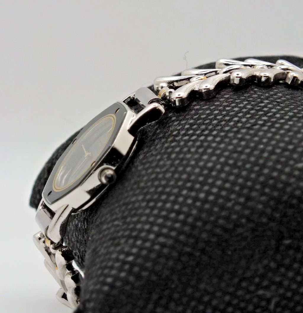 Silver-tone vintage Citizen Exceed women’s quartz black dial bracelet with linked metal band and screw accents on textured surface.