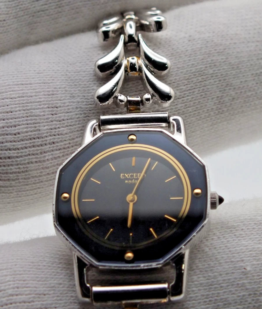 Silver-tone vintage Citizen Exceed women’s quartz black dial bracelet with gold hour markers and “EXCEED” text on black dial.