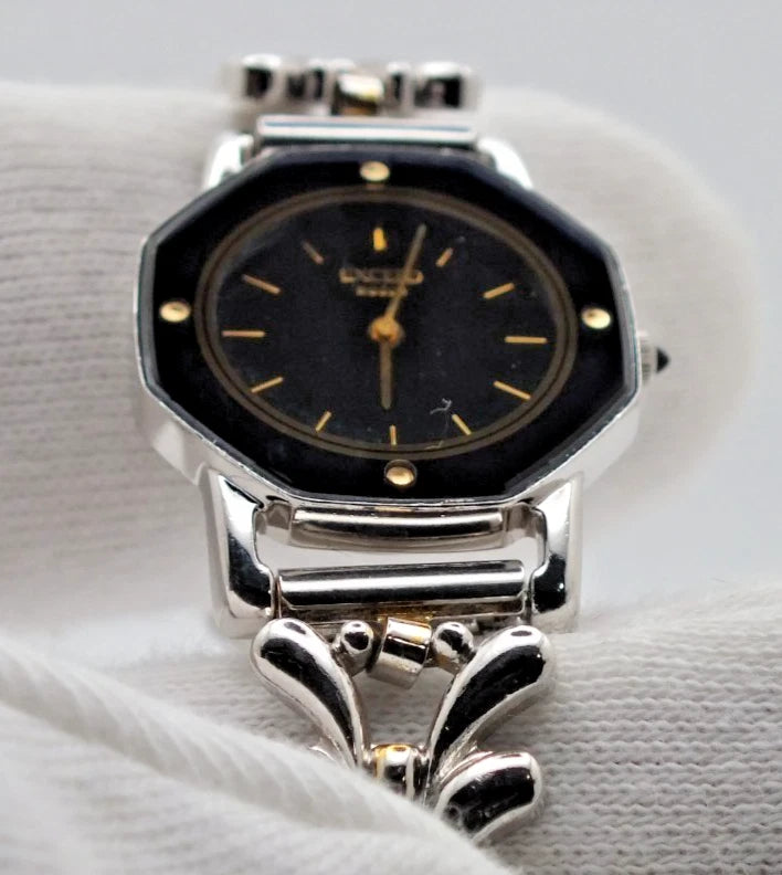Silver-tone vintage Citizen Exceed women’s quartz black dial bracelet with gold accents and linked metal band.