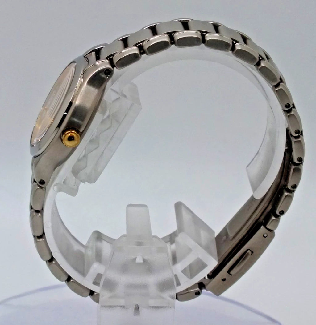 Silver titanium Citizen Exceed A930 watch with gold pearl dial, crystal bezel, and linked metal band on display stand.