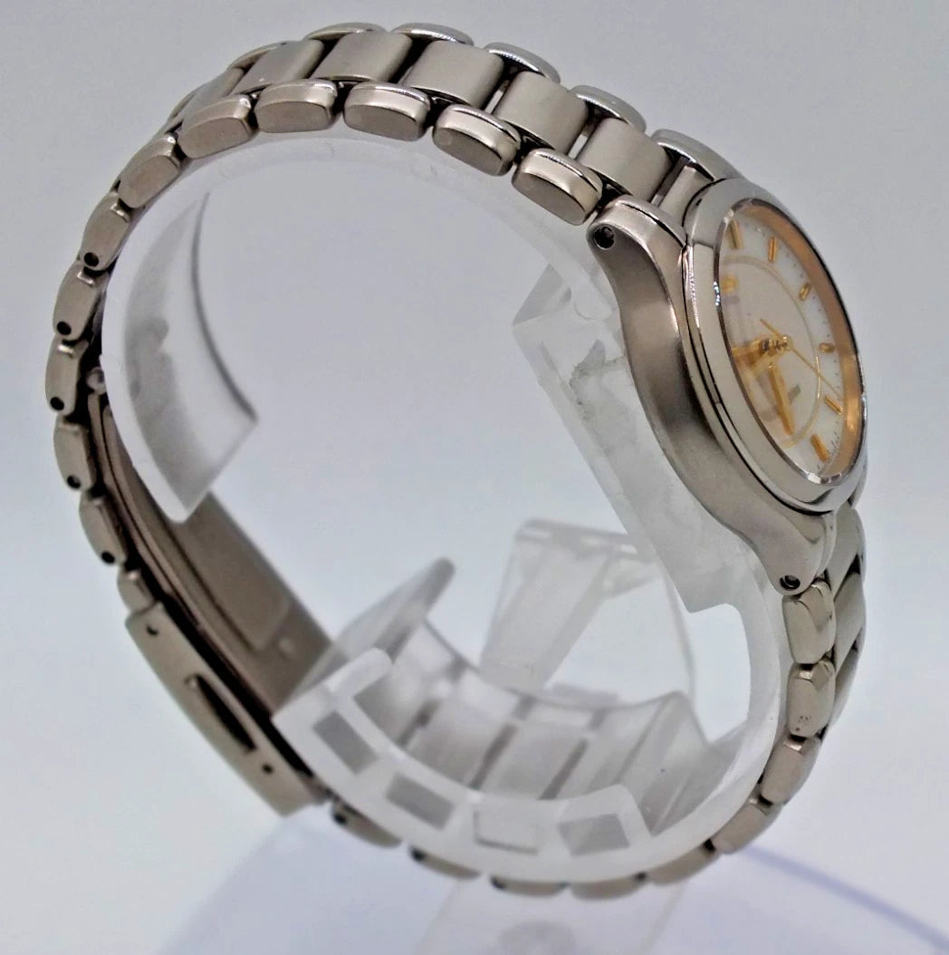 Silver titanium Citizen Exceed A930 watch with gold pearl dial, black hour markers, and stainless steel bracelet.
