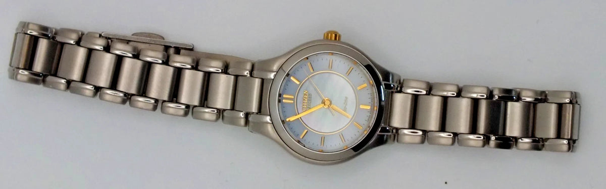 Silver titanium Citizen Exceed A930 watch with gold pearl dial, black hour markers, and linked metal band.