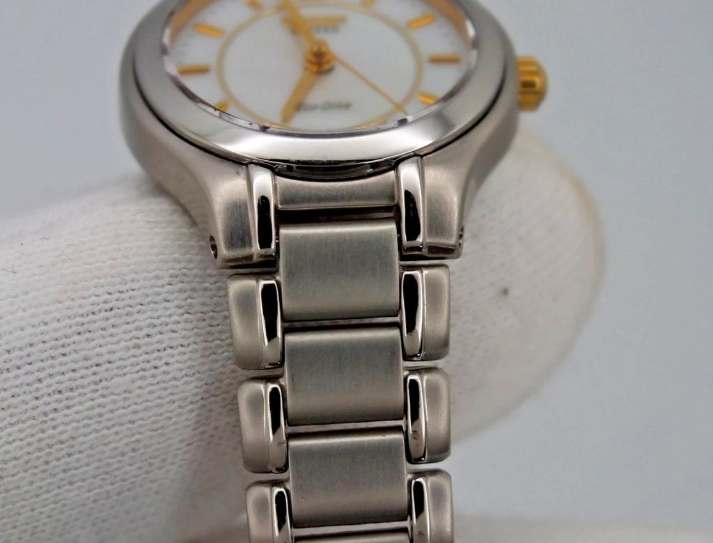 Silver titanium Citizen Exceed A930 watch with gold pearl dial, black hour markers, and stainless steel bracelet.